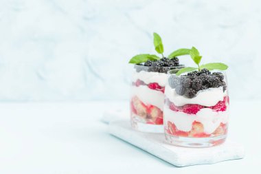 Ahududu ve böğürtlen kopya alanı pastel mavi zemin üzerine taze sağlıklı çok katmanlı tatlı önemsememek. Süt ve orman meyve - closeup fotoğrafçılık ile organik tatlı gıda.