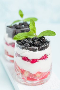 Taze sağlıklı çok katmanlı tatlı önemsememek ahududu ve böğürtlen pastel mavi arka plan ile. Süt ve orman meyve - closeup fotoğrafçılık ile organik tatlı gıda.