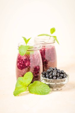 Taze yeşil nane yaprakları ve ham Olgun meyveleri yaz karışımlı vitamini kopya alanı ile kokteyl şeffaf kavanoz sarı pastel arka planda - Blueberry smoothie süslenmiş.