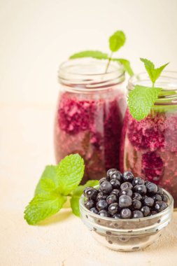Taze yeşil nane yaprakları ve ham Olgun meyveleri yaz karışımlı vitamini kopya alanı ile kokteyl şeffaf kavanoz sarı pastel arka planda - Blueberry smoothie süslenmiş.