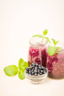 Taze yeşil nane yaprakları ve ham Olgun meyveleri yaz karışımlı vitamini kopya alanı ile kokteyl şeffaf kavanoz sarı pastel arka planda - Blueberry smoothie süslenmiş.