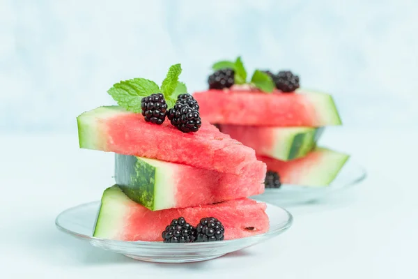 Watermelon sliced pie with blackberries and mint leaf on blue pastel background - close up macro photography of summer fresh raw ripe fruit for delicious vegetarian dessert.