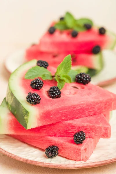 Watermelon slice pie with blackberries and mint leaf on pastel yellow background - close up macro photography of summer fresh raw ripe fruit for delicious vegetarian dessert.