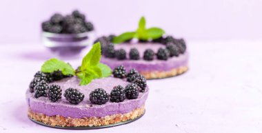 Ham blackberry tatlı taze olgun orman meyveleri ile dekore edilmiş ve pastel menekşe arka plan - tatlı Organik Gıda sağlıklı beslenme ve diyet kavramı üzerinde yeşil nane yaprakları.