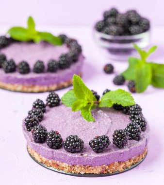 Ham blackberry tatlı taze olgun orman meyveleri ile dekore edilmiş ve pastel menekşe arka plan - tatlı Organik Gıda sağlıklı beslenme ve diyet kavramı üzerinde yeşil nane yaprakları.