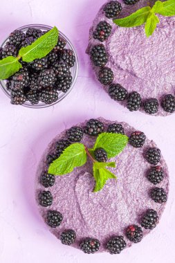 Ham blackberry tatlı taze olgun orman meyveleri ile dekore edilmiş ve pastel menekşe arka plan - tatlı Organik Gıda sağlıklı beslenme ve diyet kavramı üzerinde yeşil nane yaprakları.