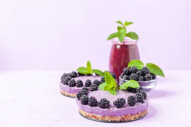 Ham blackberry tatlı taze olgun orman meyveleri ile dekore edilmiş ve yeşil nane yaprakları ve güler yüzlü pastel mor zemin - sağlıklı beslenme ve diyet kavramı için tatlı organik gıda üzerine karışık.