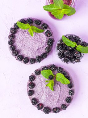 Ham blackberry tatlı taze olgun orman meyveleri ve yeşil nane yaprakları ve pastel mor zemin - üstten görünüm tatlı organik sağlıklı gıda üzerine karışık güler yüzlü süslenmiş.