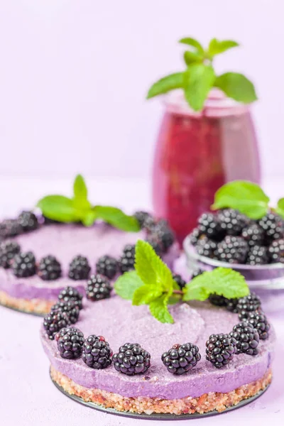 Ham blackberry tatlı taze olgun orman meyveleri ile dekore edilmiş ve yeşil nane yaprakları ve güler yüzlü pastel mor zemin - sağlıklı beslenme ve diyet kavramı için tatlı organik gıda üzerine karışık.