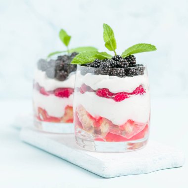 Taze sağlıklı çok katmanlı tatlı önemsememek ahududu ve böğürtlen pastel mavi arka plan ile. Süt ve orman meyve - closeup fotoğrafçılık ile organik tatlı gıda.