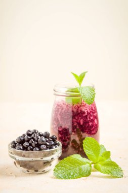 Taze yeşil nane yaprakları ve ham Olgun meyveleri yaz karışımlı vitamini kopya alanı ile kokteyl şeffaf kavanoz sarı pastel arka planda - Blueberry smoothie süslenmiş.