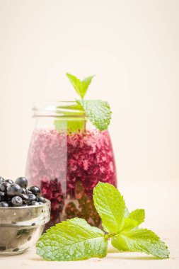 Taze yeşil nane yaprakları ve ham Olgun meyveleri yaz karışımlı vitamini kopya alanı ile kokteyl şeffaf kavanoz sarı pastel arka planda - Blueberry smoothie süslenmiş.