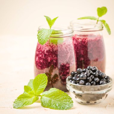 Taze yeşil nane yaprakları ve ham Olgun meyveleri yaz karışımlı vitamini kopya alanı ile kokteyl şeffaf kavanoz sarı pastel arka planda - Blueberry smoothie süslenmiş.