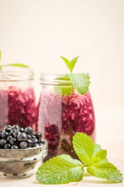 Taze yeşil nane yaprakları ve ham Olgun meyveleri yaz karışımlı vitamini kopya alanı ile kokteyl şeffaf kavanoz sarı pastel arka planda - Blueberry smoothie süslenmiş.