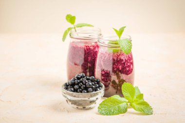 Taze yeşil nane yaprakları ve ham Olgun meyveleri yaz karışımlı vitamini kopya alanı ile kokteyl şeffaf kavanoz sarı pastel arka planda - Blueberry smoothie süslenmiş.