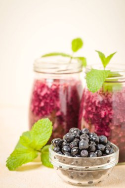 Taze yeşil nane yaprakları ve ham Olgun meyveleri yaz karışımlı vitamini kopya alanı ile kokteyl şeffaf kavanoz sarı pastel arka planda - Blueberry smoothie süslenmiş.