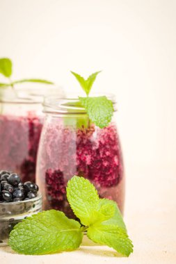Taze yeşil nane yaprakları ve ham Olgun meyveleri yaz karışımlı vitamini kopya alanı ile kokteyl şeffaf kavanoz sarı pastel arka planda - Blueberry smoothie süslenmiş.