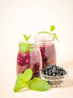 Taze yeşil nane yaprakları ve ham Olgun meyveleri yaz karışımlı vitamini kopya alanı ile kokteyl şeffaf kavanoz sarı pastel arka planda - Blueberry smoothie süslenmiş.
