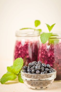Taze yeşil nane yaprakları ve ham Olgun meyveleri yaz karışımlı vitamini kopya alanı ile kokteyl şeffaf kavanoz sarı pastel arka planda - Blueberry smoothie süslenmiş.
