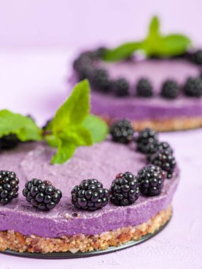 Ham blackberry tatlı taze olgun orman meyveleri ile dekore edilmiş ve pastel menekşe arka plan - tatlı Organik Gıda sağlıklı beslenme ve diyet kavramı üzerinde yeşil nane yaprakları.