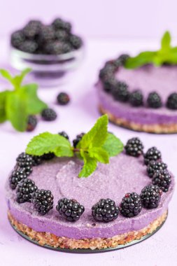 Ham blackberry tatlı taze olgun orman meyveleri ile dekore edilmiş ve pastel menekşe arka plan - tatlı Organik Gıda sağlıklı beslenme ve diyet kavramı üzerinde yeşil nane yaprakları.