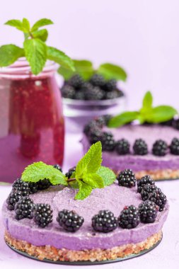 Ham blackberry tatlı taze olgun orman meyveleri ile dekore edilmiş ve yeşil nane yaprakları ve güler yüzlü pastel mor zemin - sağlıklı beslenme ve diyet kavramı için tatlı organik gıda üzerine karışık.