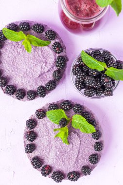 Ham blackberry tatlı taze olgun orman meyveleri ve yeşil nane yaprakları ve pastel mor zemin - üstten görünüm tatlı organik sağlıklı gıda üzerine karışık güler yüzlü süslenmiş.