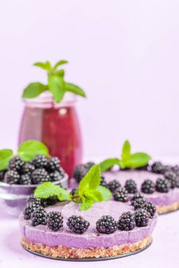 Ham blackberry tatlı taze olgun orman meyveleri ile dekore edilmiş ve yeşil nane yaprakları ve güler yüzlü pastel mor zemin - sağlıklı beslenme ve diyet kavramı için tatlı organik gıda üzerine karışık.