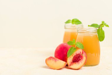 Taze olgunlaşmış meyve ve yeşil nane yaprakları sarı pastel arka plan - ham şekerli tatlı veya kahvaltı içki sağlıklı organik beslenme kavramı üzerinde cam kavanozlara şeftali yüzlü.