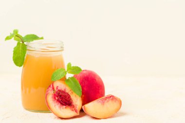 Taze olgunlaşmış meyve ve yeşil nane yaprakları sarı pastel arka plan - ham şekerli tatlı veya kahvaltı içki sağlıklı organik beslenme kavramı üzerinde cam kavanozlara şeftali yüzlü.