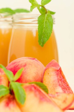 Taze olgunlaşmış meyve ve yeşil nane yaprakları sarı pastel arka plan - ham şekerli tatlı veya kahvaltı içki sağlıklı organik beslenme kavramı üzerinde cam kavanozlara şeftali yüzlü.