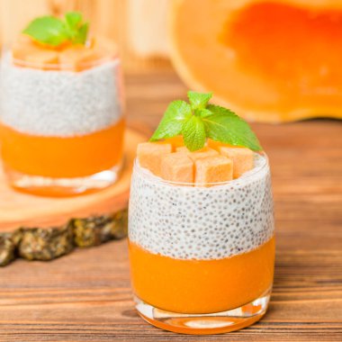 Chia puding güzel gözlük yeşil nane yaprakları ve kahverengi ahşap arka plan - ham vejetaryen tatlı sağlıklı organik tatlı taze olgun sebze ile kabak püresi ile.