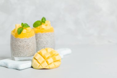 Chia tohum puding mango ile güzel gözlük yeşil nane yaprakları ile püre ve açık gri renkli - ham vejetaryen şekerli organik tatlı taze olgun tropikal meyve kesme.