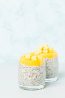 Chia tohum puding ile mango püresi ve pastel mavi arka plan - ham vejetaryen şekerli organik tatlı güzel Gözlüklü olgun taze tropikal meyve kesme.