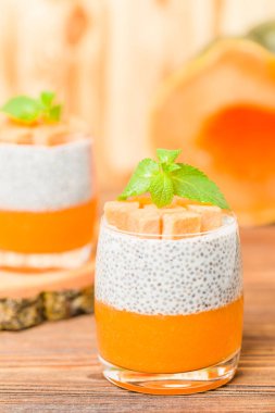 Chia puding güzel gözlük yeşil nane yaprakları ve kahverengi ahşap arka plan - ham vejetaryen tatlı sağlıklı organik tatlı taze olgun sebze ile kabak püresi ile.