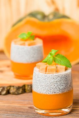 Chia puding güzel gözlük yeşil nane yaprakları ve kahverengi ahşap arka plan - ham vejetaryen tatlı sağlıklı organik tatlı taze olgun sebze ile kabak püresi ile.