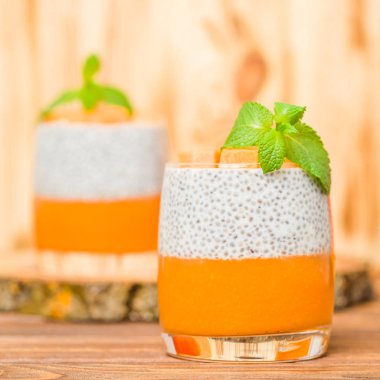Chia puding güzel gözlük yeşil nane yaprakları ve kahverengi ahşap arka plan - ham vejetaryen tatlı sağlıklı organik tatlı taze olgun sebze ile kabak püresi ile.