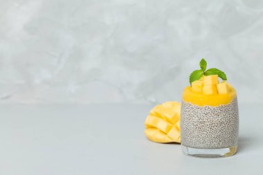 Chia tohum puding mango ile güzel gözlük yeşil nane yaprakları ile püre ve açık gri renkli - ham vejetaryen şekerli organik tatlı taze olgun tropikal meyve kesme.