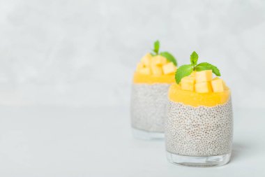 Chia tohum puding mango ile güzel gözlük yeşil nane yaprakları ile püre ve açık gri renkli - ham vejetaryen şekerli organik tatlı taze olgun tropikal meyve kesme.