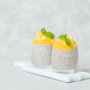 Chia tohum puding mango ile güzel gözlük yeşil nane yaprakları ile püre ve açık gri renkli - ham vejetaryen şekerli organik tatlı taze olgun tropikal meyve kesme.