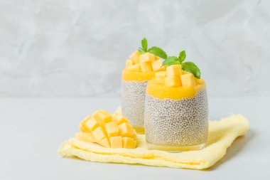 Chia tohum puding mango ile güzel gözlük yeşil nane yaprakları ile püre ve açık gri renkli - ham vejetaryen şekerli organik tatlı taze olgun tropikal meyve kesme.
