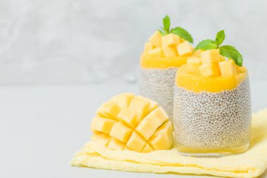 Chia tohum puding mango ile güzel gözlük yeşil nane yaprakları ile püre ve açık gri renkli - ham vejetaryen şekerli organik tatlı taze olgun tropikal meyve kesme.