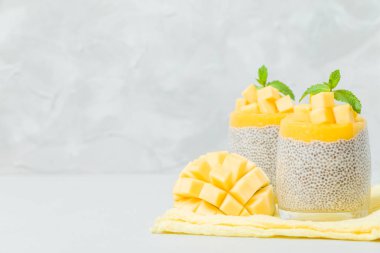Chia tohum puding mango ile güzel gözlük yeşil nane yaprakları ile püre ve açık gri renkli - ham vejetaryen şekerli organik tatlı taze olgun tropikal meyve kesme.