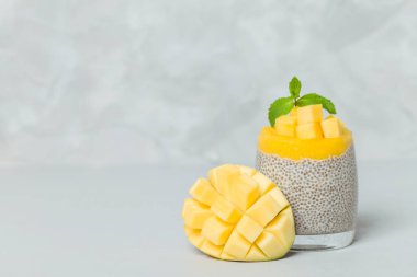 Chia tohum puding mango ile güzel gözlük yeşil nane yaprakları ile püre ve açık gri renkli - ham vejetaryen şekerli organik tatlı taze olgun tropikal meyve kesme.
