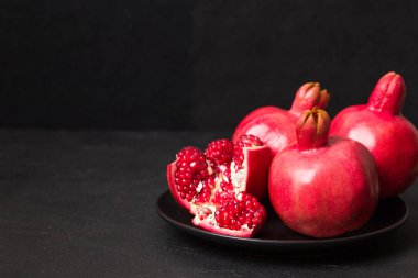 Olgun kırmızı nar closeup Fotoğrafçılık kopya alanı - mevsimlik ham bütün ve kesme sulu meyve tohumları metin için boş yer karanlık ruh tarzı ile siyah zemin üzerine.