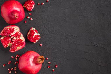Olgun kırmızı nar closeup Fotoğrafçılık kopya alanı - üstten görünüm mevsimlik ham bütün ve kesme sulu meyve tohumları metin için boş yer karanlık ruh tarzı ile siyah zemin üzerine.