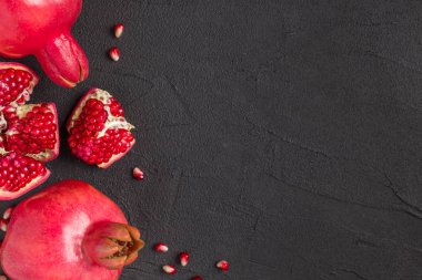 Olgun kırmızı nar closeup Fotoğrafçılık kopya alanı - üstten görünüm mevsimlik ham bütün ve kesme sulu meyve tohumları metin için boş yer karanlık ruh tarzı ile siyah zemin üzerine.