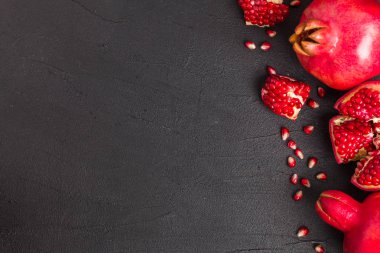 Olgun kırmızı nar closeup Fotoğrafçılık kopya alanı - üstten görünüm mevsimlik ham bütün ve kesme sulu meyve tohumları metin için boş yer karanlık ruh tarzı ile siyah zemin üzerine.