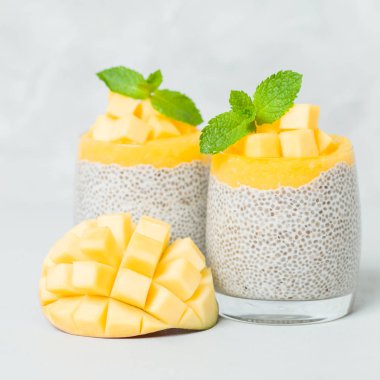 Chia tohum puding mango ile güzel gözlük yeşil nane yaprakları ile püre ve açık gri renkli - ham vejetaryen şekerli organik tatlı taze olgun tropikal meyve kesme.