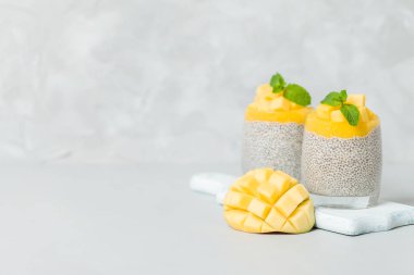 Chia tohum puding mango ile güzel gözlük yeşil nane yaprakları ile püre ve açık gri renkli - ham vejetaryen şekerli organik tatlı taze olgun tropikal meyve kesme.
